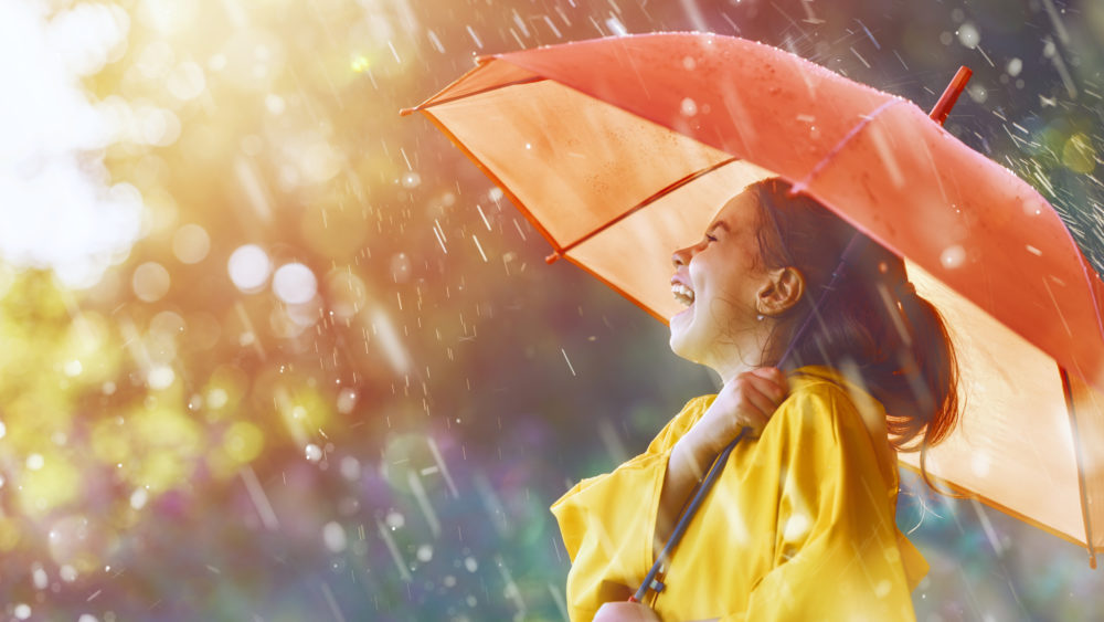 Laughing girl holding an umbrella in the rain