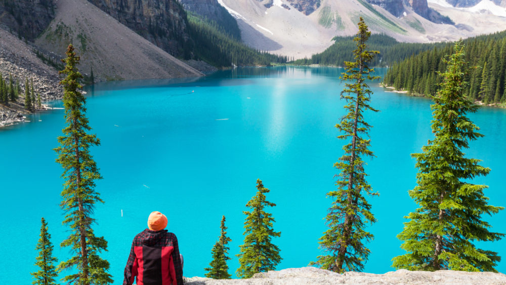 A hiker enjoying the view of Moraine Lake in Banff National Park, Canada.
