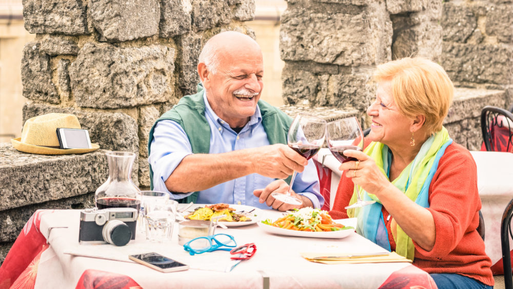 An older couple eating at a restaurant while on holiday.