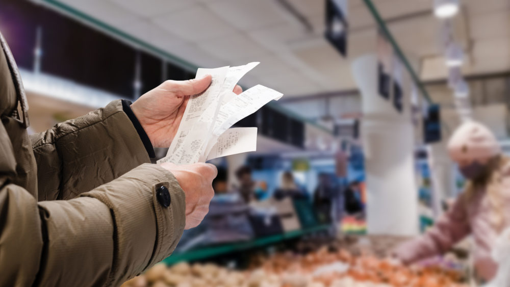 A person holding up a receipt in a supermarket.