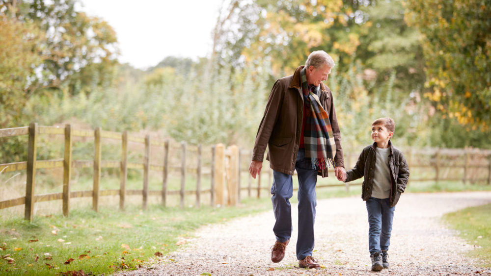 Grandfather walking with grandson in the countryside