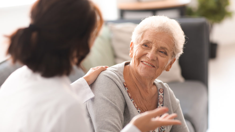 An older woman talking to a doctor at home.