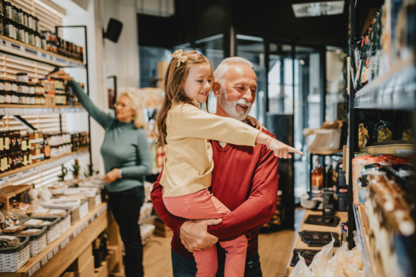 A grandfather grocery shopping with his granddaughter.