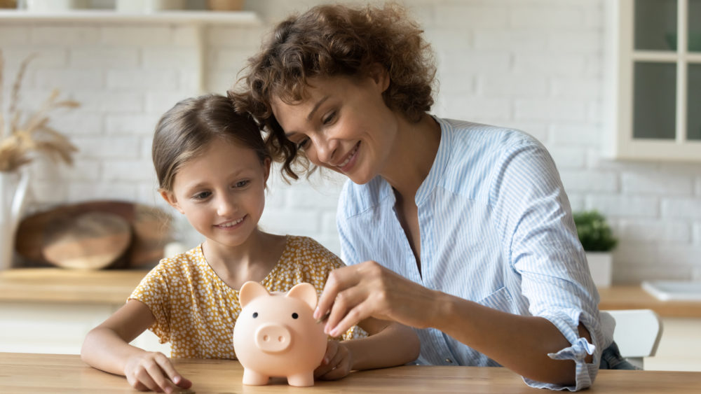 Mother and daughter saving in a piggy bank