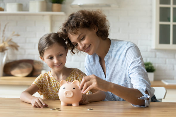 Mother and daughter saving in a piggy bank