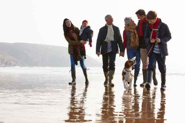 A multi-generation family walking together on a beach.