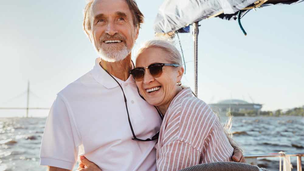 An older couple hugging on a boat.