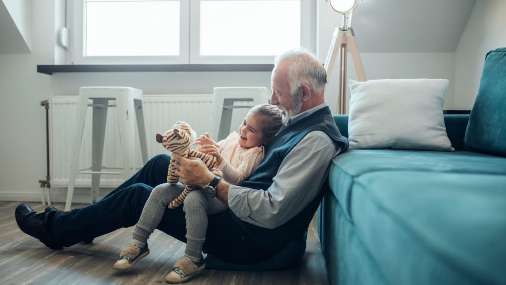 A grandfather playing with his granddaughter.