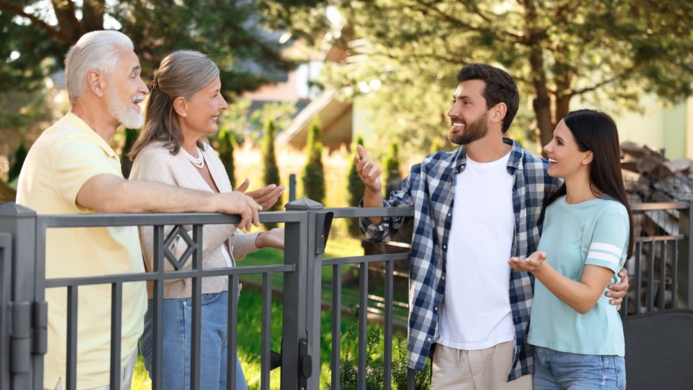 A young couple talking to their older neighbours.