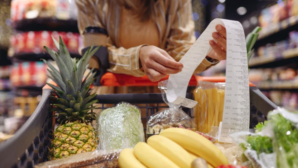 A woman looking at a receipt in a supermarket.