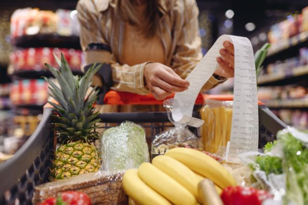 A woman looking at a receipt in a supermarket.