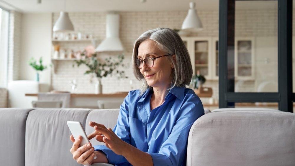 A woman in her 60s checking something on her mobile phone.