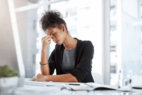 A woman pinching the bridge of her nose in an office.