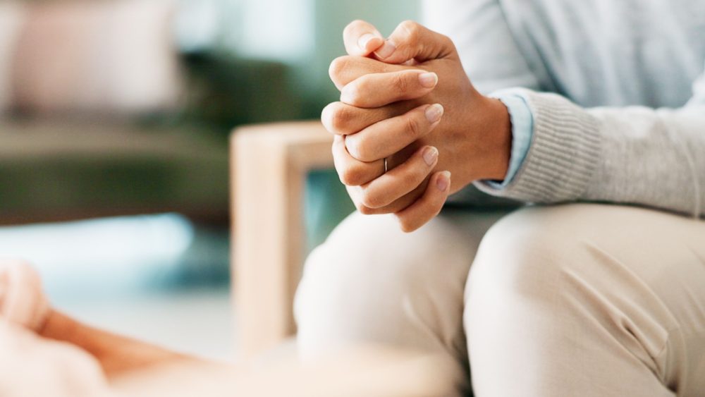 A woman sitting with her hands clasped.