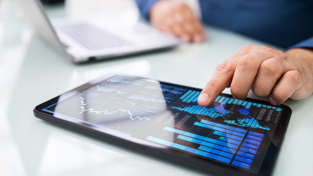 A man looking at graphs on a tablet.