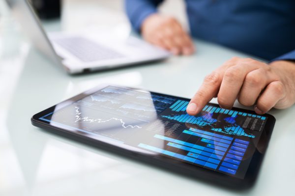 A man looking at graphs on a tablet.