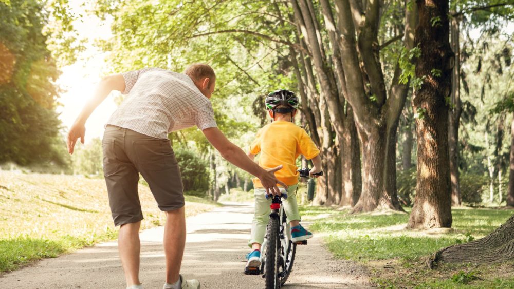 A father teaching a child to ride a bike.