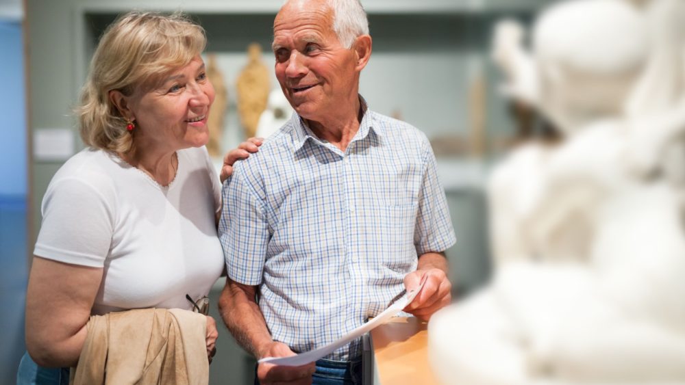 A couple looking at a statue in a museum.