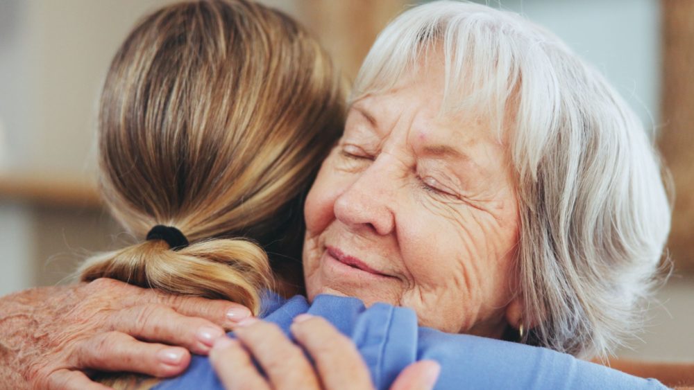 A senior woman hugging a caregiver.