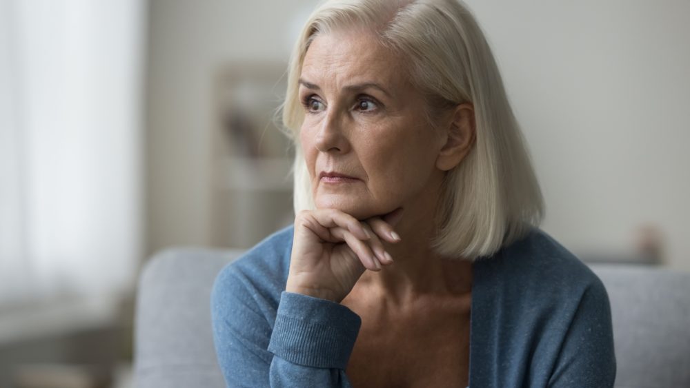An older woman looks pensively off to one side.
