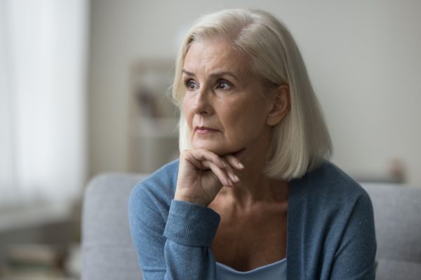 An older woman looks pensively off to one side.