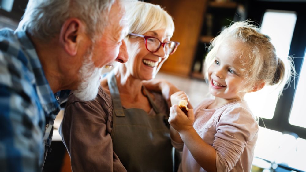 Happy smiling grandparents enjoying time with grandchild at home